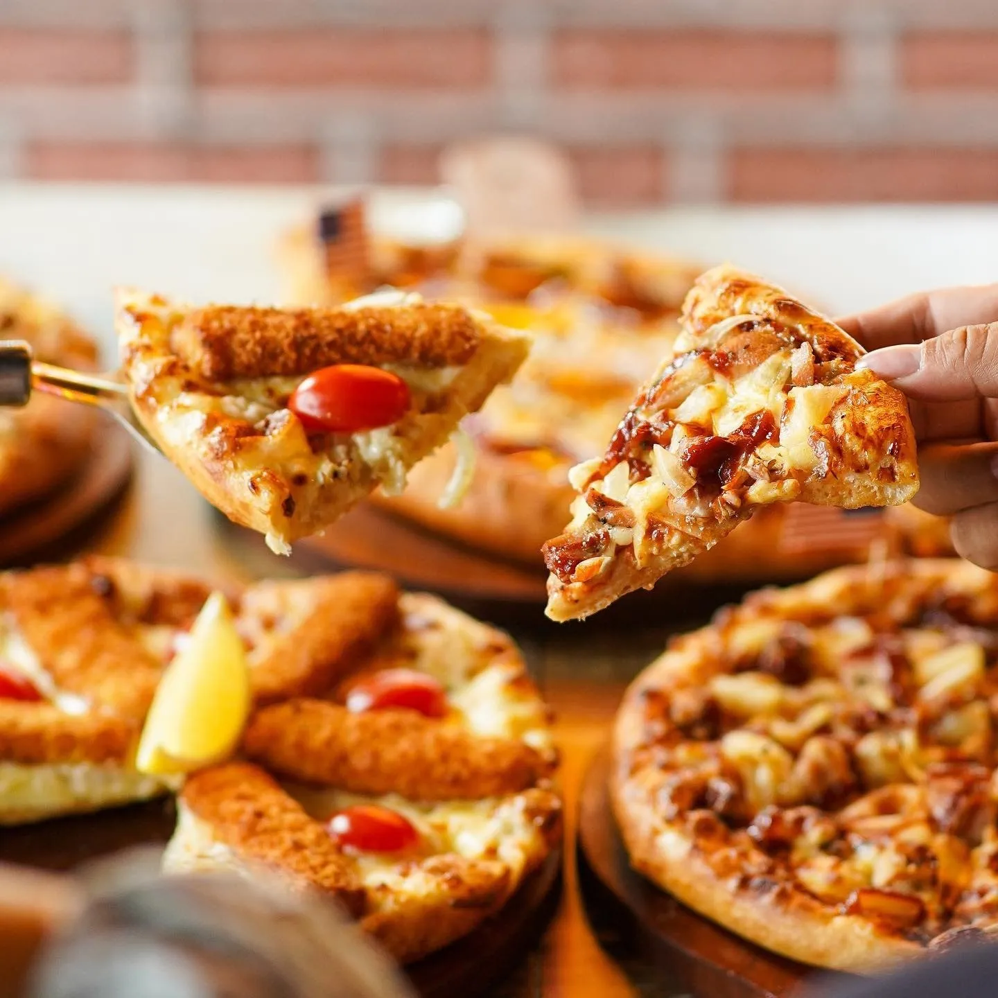 A spread of US Pizza pizzas with two slices lifted